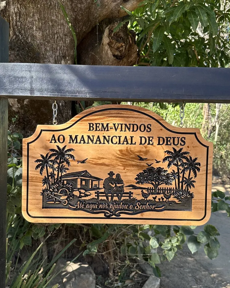 Placa de madeira entalhada Bem-vindos ao Manancial de Deus na entrada de um sítio